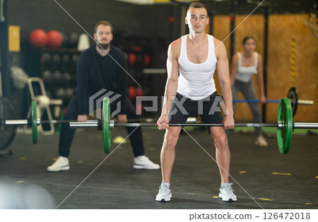 Man performing deadlift with barbell at group functional training 126472018