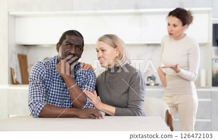 Elderly woman calms man during quarrel with adult woman 126472103
