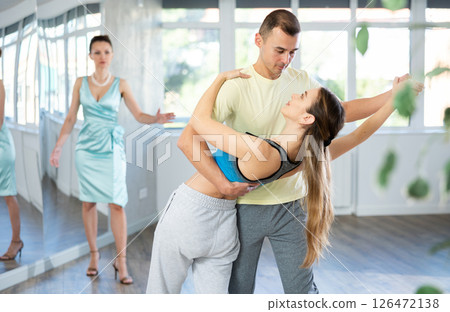 Smiling couple rehearsing wedding waltz in dance studio Smiling couple rehearsing wedding waltz in dance studio 126472138