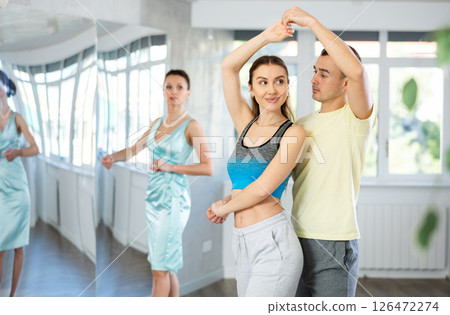 Couple in comfortable sports clothes waltz dancing during individual lesson Couple in comfortable sports clothes waltz dancing during individual lesson 126472274