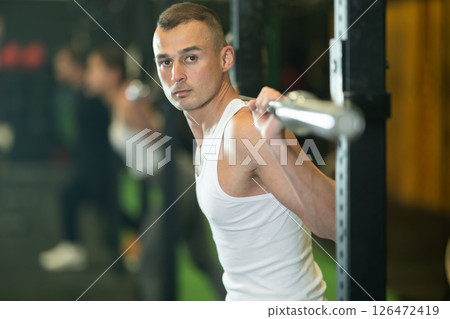 Athletic man performing exercises with barbell at training in gym Athletic man performing exercises with barbell at training in gym 126472419