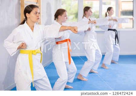 Adolescent karateka practicing punches during kata at group training Adolescent karateka practicing punches during kata at group training 126472424