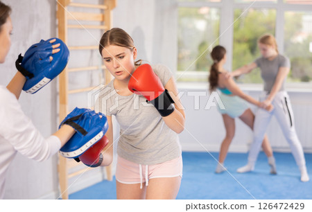 Teen girl in punch mitts boxing Teen girl in punch mitts boxing 126472429