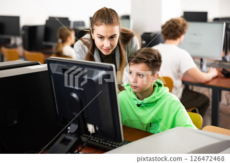 Female teacher consulting tween boy studying in computer class 126472468