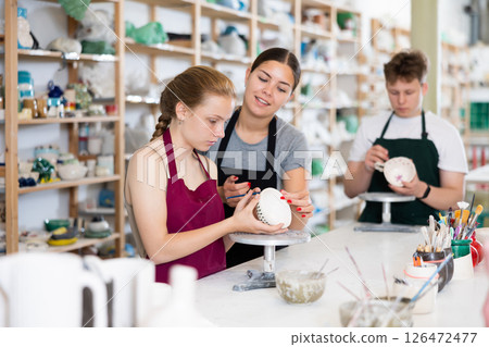 Master potter teaches teen girl how to draw and glaze pottery 126472477