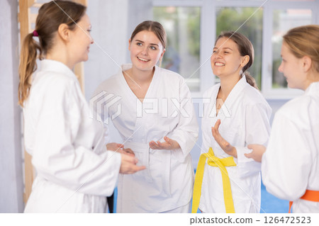 Group of young women are talking after successful and tedious karate workout. Group of young women are talking after successful and tedious karate workout. 126472523
