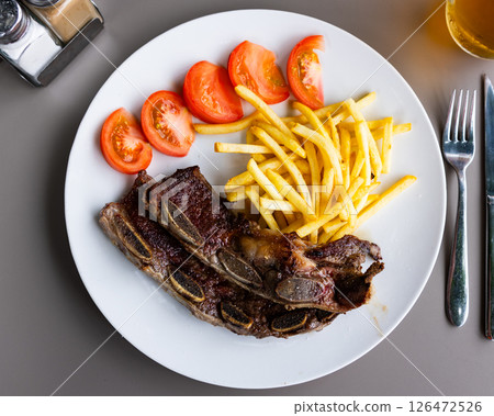Grilled beef ribs Churasko are garnished with French fries and tomato 126472526