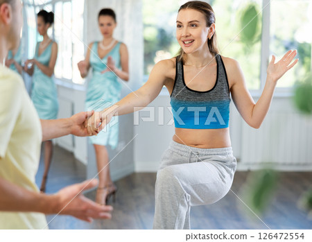 Couple in comfortable sports clothes learns boogie woogie dancing during individual lesson 126472554