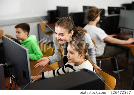 Positive woman teacher together with the girl teaches how to work on computer 126472557
