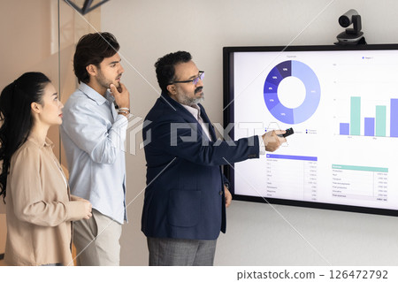 Male professional presenting financial data on digital screen to colleagues 126472792