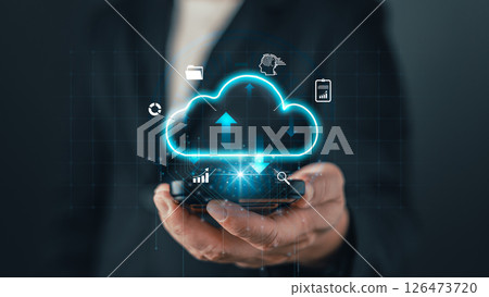 A businessman holds a smartphone with a glowing cloud icon, symbolizing cloud computing, data storage, digital solutions, and online technology for modern business and virtual connectivity A businessman holds a smartphone with a glowing cloud icon, symbolizing cloud computing, data storage, digital solutions, and online technology for modern business and virtual connectivity 126473720