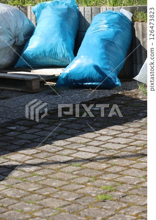 A pile of blue plastic bags sit on a brick walkway A pile of blue plastic bags sit on a brick walkway 126473823