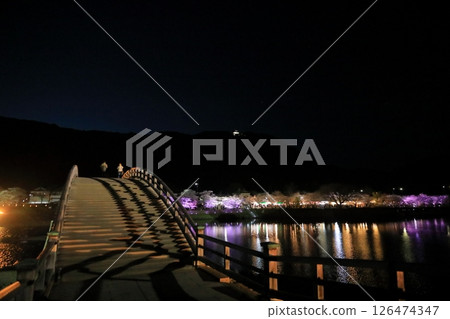 People crossing Kintai Bridge to see the illuminated cherry blossoms at night People crossing Kintai Bridge to see the illuminated cherry blossoms at night 126474347