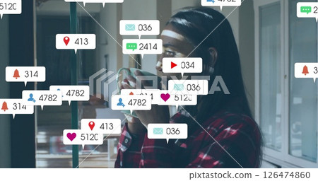 Social media notifications image over woman drinking coffee by window 126474860