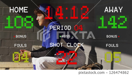 Scoreboard image over baseball player sitting in dugout with bat and glove 126474862