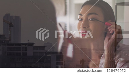 Applying mascara, woman in cityscape image 126474952