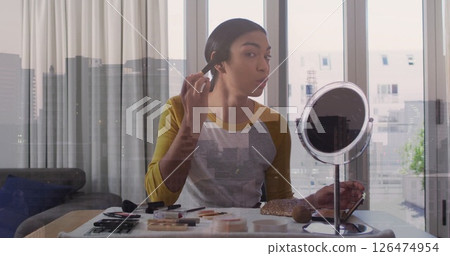 Applying makeup at vanity, person over cityscape image 126474954