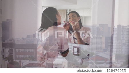 Applying makeup, woman reflected in mirror over cityscape image Applying makeup, woman reflected in mirror over cityscape image 126474955