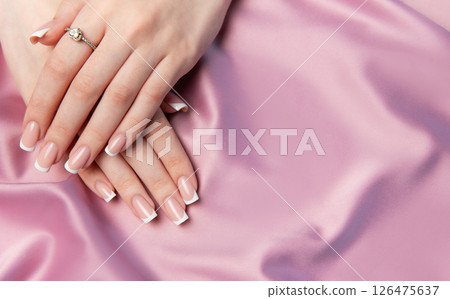 Woman showing french manicure on pink satin background 126475637