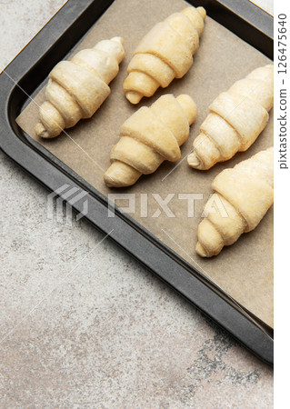 Raw croissants resting on baking sheet awaiting oven's warmth 126475640