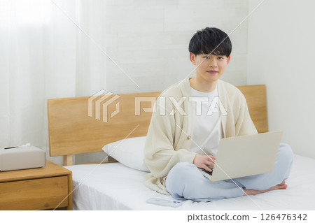 Man using laptop in bed 126476342