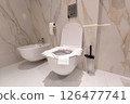 A clean modern toilet with paper-covered seat in a marble bathroom interior for hygiene protection 126477741