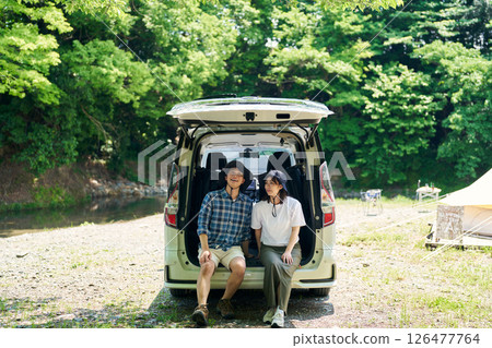 Men and women relaxing in a car at a campsite 126477764