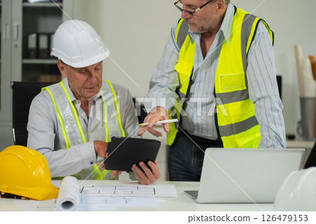 Engineering team collaborates on blueprint and project planning. 126479153