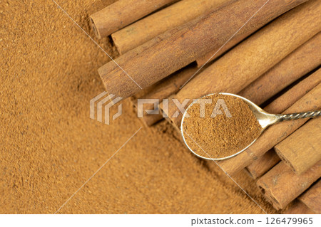 Ground cinnamon spice in a spoon and cinnamon sticks, top view Ground cinnamon spice in a spoon and cinnamon sticks, top view 126479965