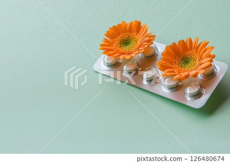 pills in a blister pack with orange flowers on green background, allergy to flowers 126480674
