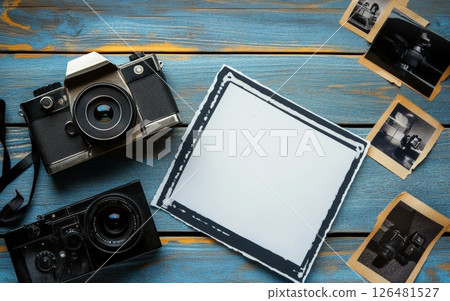 Retro film cameras with a blank photo frame and old photographs on blue wooden background, perfect for photography or nostalgia concept with copy space 126481527