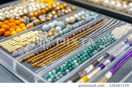Organized trays of vibrant beads, gemstones, and jewelry making materials showcasing a diverse array of colors, shapes, and textures for crafting Organized trays of vibrant beads, gemstones, and jewelry making materials showcasing a diverse array of colors, shapes, and textures for crafting 126481539