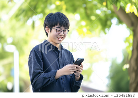 A male student wearing a black shirt with a bright expression and holding a smartphone A male student wearing a black shirt with a bright expression and holding a smartphone 126481688