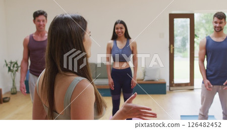 Caucasian female yoga instructor talking to happy diverse group during yoga class at studio Caucasian female yoga instructor talking to happy diverse group during yoga class at studio 126482452