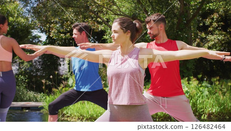 Diverse group practicing yoga pose in sunny park with asian female instructor helping Diverse group practicing yoga pose in sunny park with asian female instructor helping 126482464
