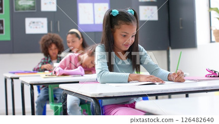 In school, girl writing in notebook at desk, focusing on classroom work 126482640
