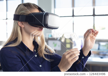 Woman using VR headset in modern office, interacting with virtual objects Woman using VR headset in modern office, interacting with virtual objects 126483496