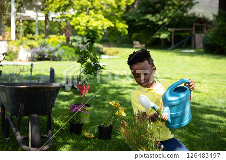 Young boy watering plants in garden, enjoying outdoor gardening activity, copy space Young boy watering plants in garden, enjoying outdoor gardening activity, copy space 126483497