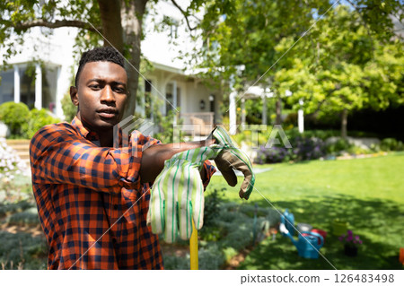 Man in garden putting on gloves, preparing for outdoor gardening work 126483498