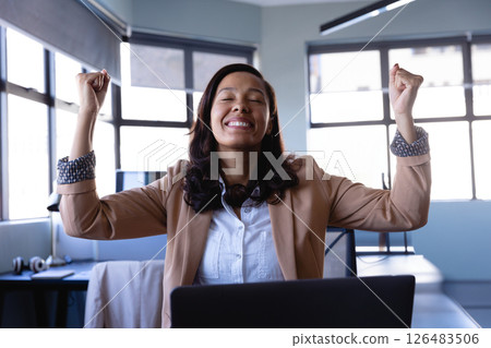 Celebrating achievement at desk, businesswoman in office with joyful expression 126483506
