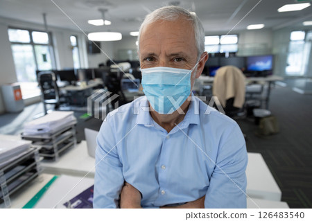 Senior man wearing mask standing confidently in modern office environment 126483540