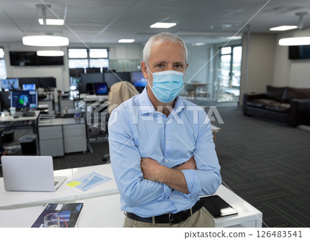 Senior man wearing mask standing confidently in modern office environment 126483541