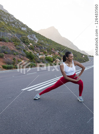 Woman stretching on mountain road, enjoying outdoor fitness in nature, copy space 126483560