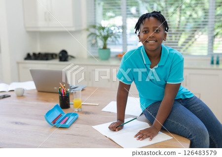 Smiling boy drawing at home on table with pencils and laptop nearby, copy space Smiling boy drawing at home on table with pencils and laptop nearby, copy space 126483579