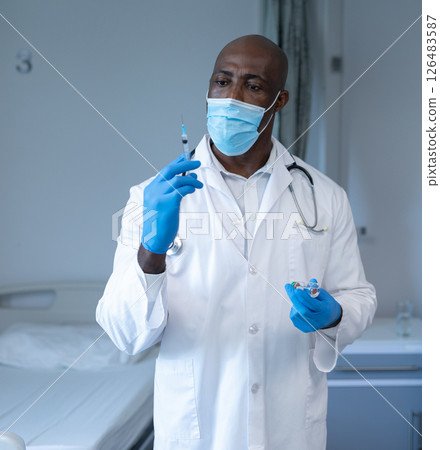 In hospital, doctor wearing mask preparing syringe with focus and precision 126483587
