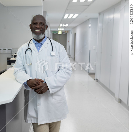 Doctor in white coat smiling confidently in hospital corridor, ready to assist 126483589
