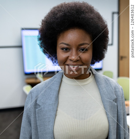 African American woman smiling confidently in office, wearing professional attire African American woman smiling confidently in office, wearing professional attire 126483612