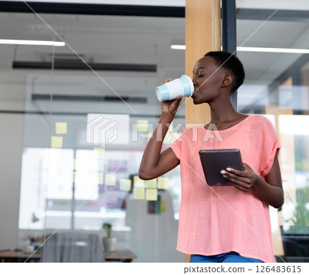 African American woman drinking coffee and holding tablet in modern office, copy space African American woman drinking coffee and holding tablet in modern office, copy space 126483615