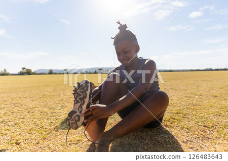 African American girl tying shoelaces on field, preparing for outdoor activity 126483643