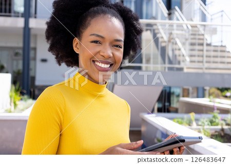 Smiling woman holding tablet outdoors, enjoying sunny day at modern office Smiling woman holding tablet outdoors, enjoying sunny day at modern office 126483647